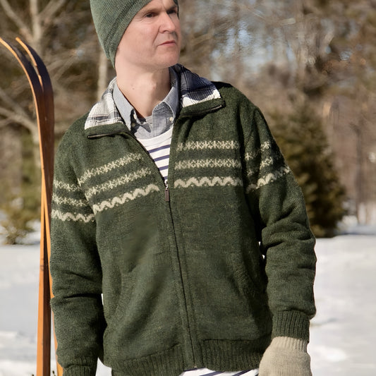 Person wearing a green knitted jacket with a patterned design, standing outdoors in a snowy landscape.